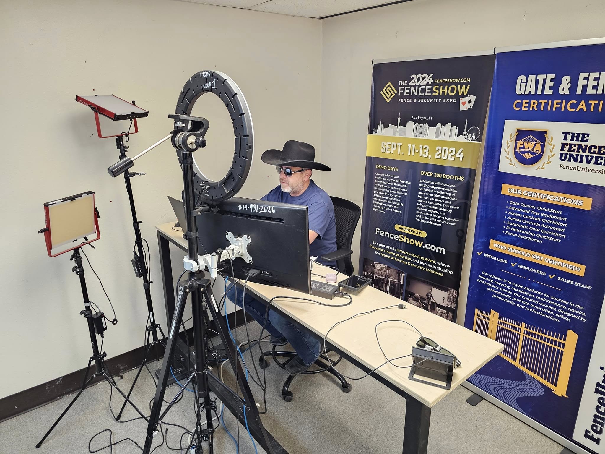 Brian at his desk with ring light, monitors and FenceShow banners